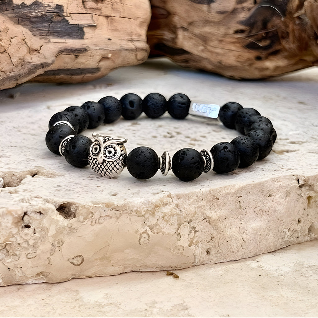 Bracelet mixte en perles noires de pierre volcanique mat avec un hibou protecteur argenté central et des intercalaires.
