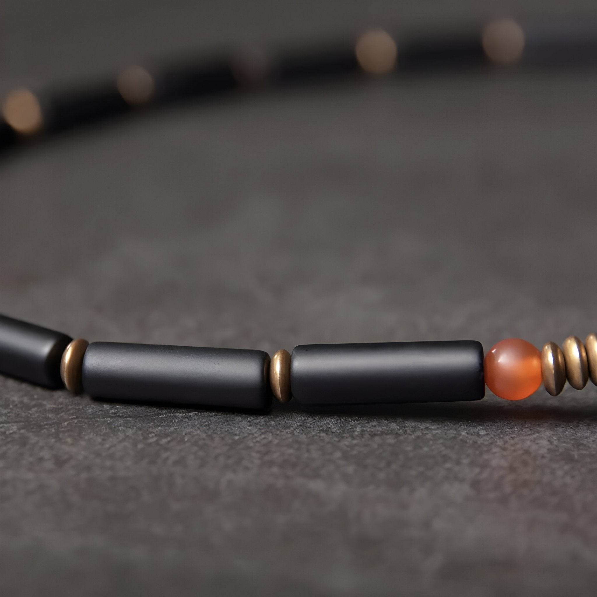 Bracelet femme en pierres d'agate noires cylindriques, perles cuivre doré, et agate orange translucide.