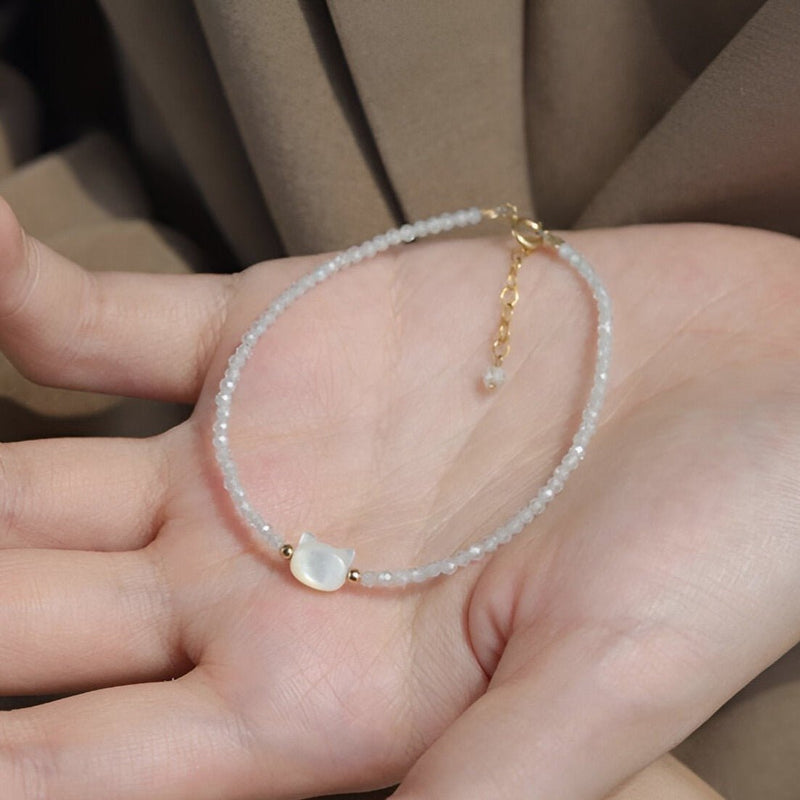 Bracelet femme en pierres de cristal blanches avec tête de chat nacrée et chaîne dorée ajustable.