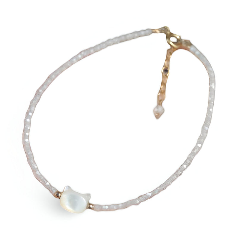 Bracelet femme avec perles blanches et tête de chat en cristal nacré sur chaîne fine dorée.
