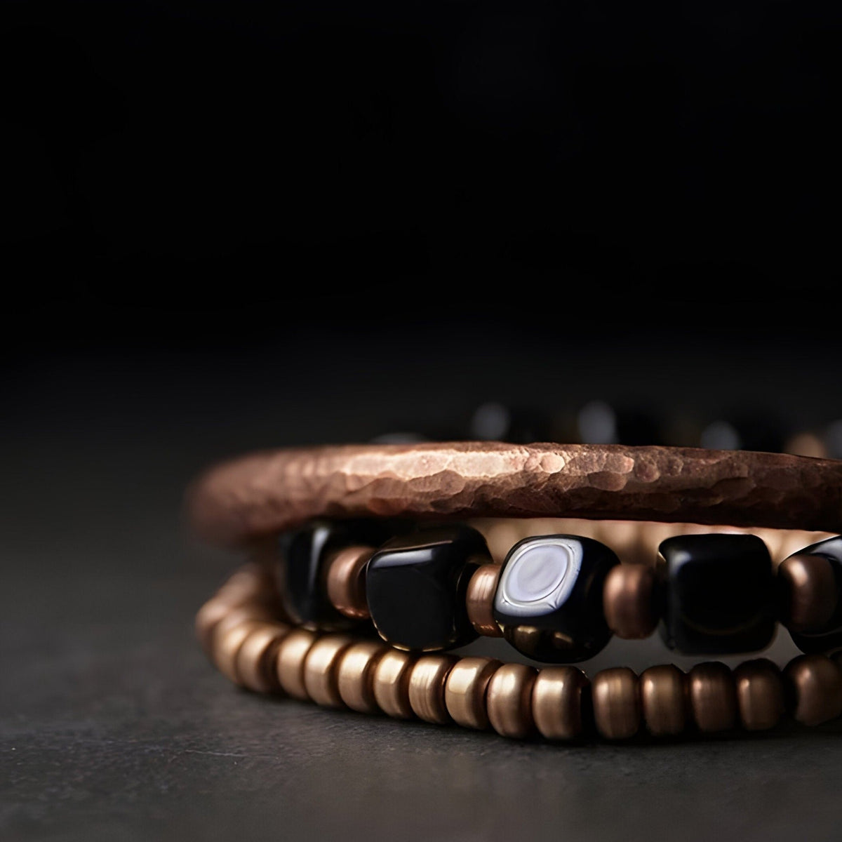 Bracelet femme mêlant perles noires d'onyx et cuivre martelé finition brillante.
