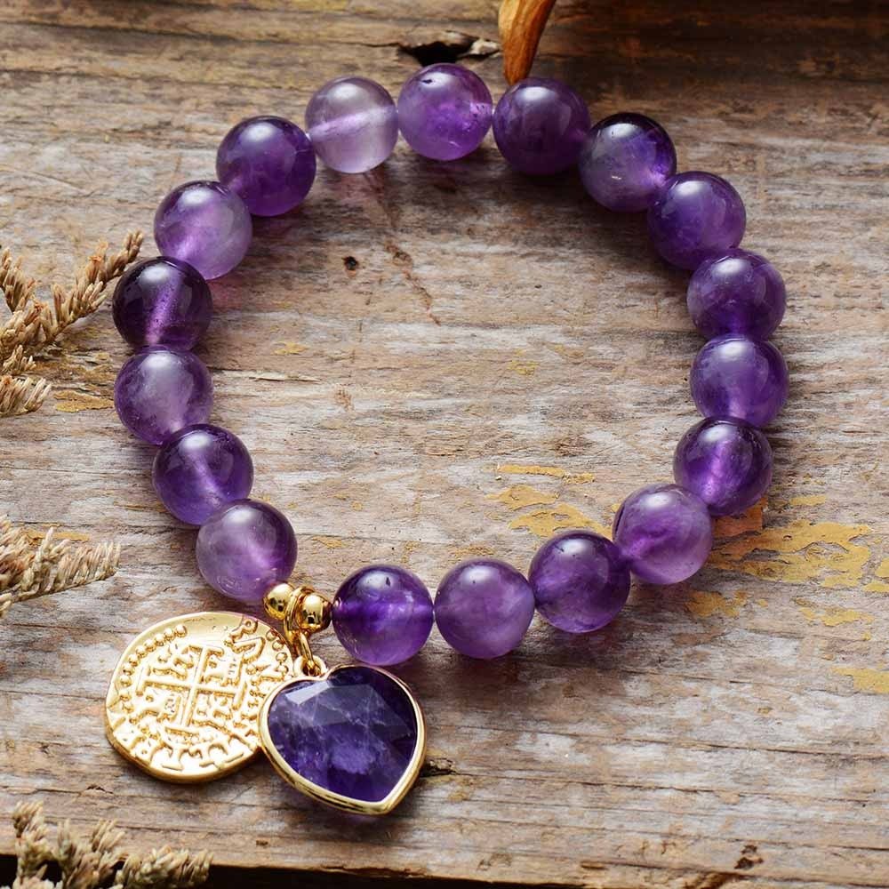 Bracelet élastique en perles rondes d’améthyste 10 mm avec pendentif cœur en pierre et médaille dorée gravée.