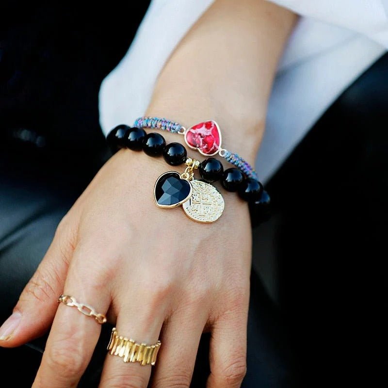 Bracelet élastique en pierres d'onyx noires 10mm avec pendentifs cœur rouge et médaille dorée.