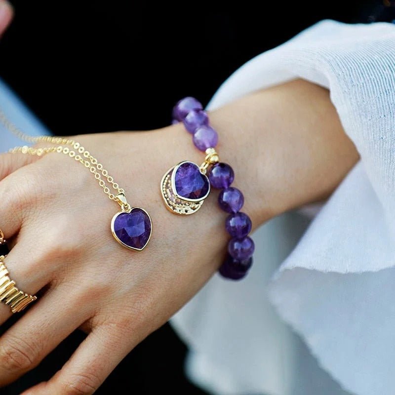 Bracelet élastique en améthyste 10mm avec pendentif cœur violet et détail doré.