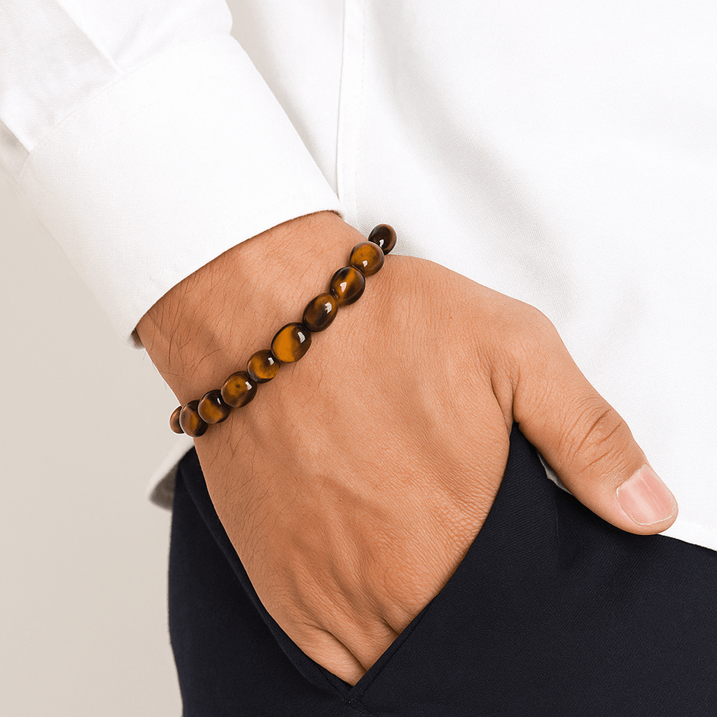 Bracelet en œil de tigre avec perles rondes lisses sur poignet, style asymétrique, ton marron brillant.