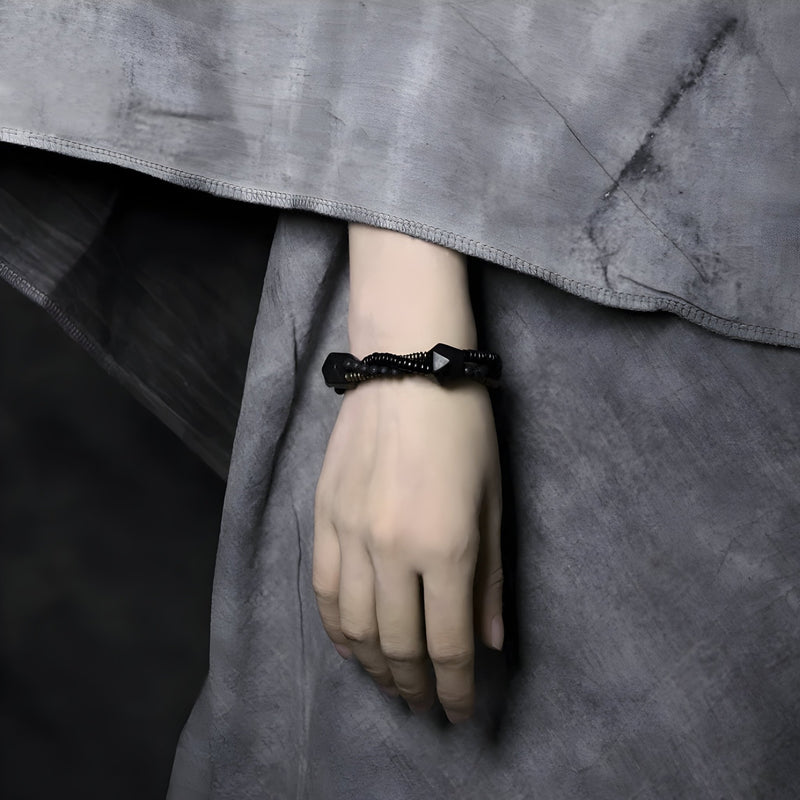 Bracelet femme en pierres naturelles noires et bois d’ébène tressé sur poignet.