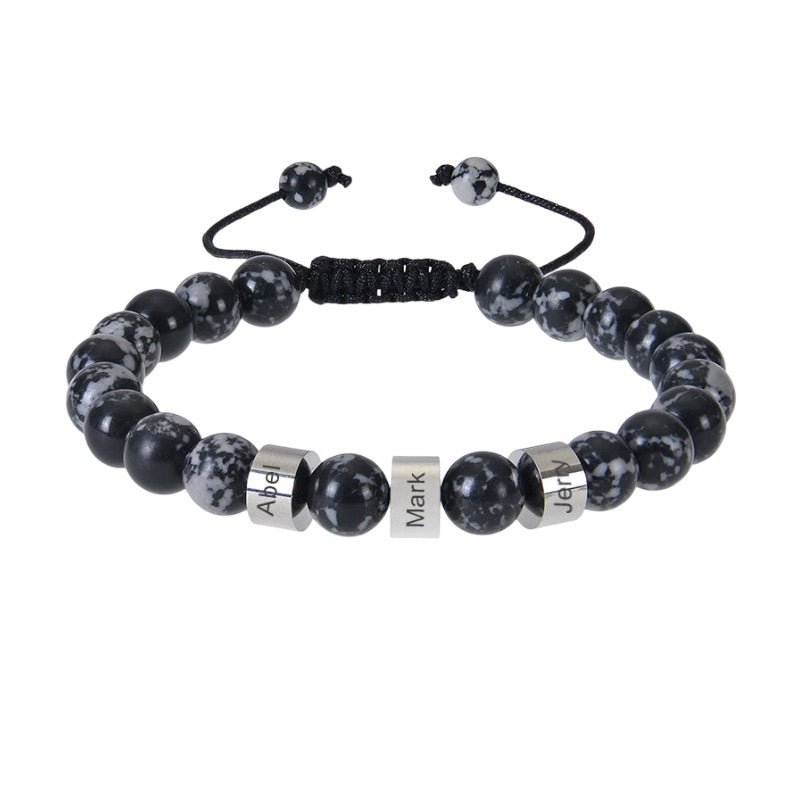 Bracelet en pierres naturelles noires avec perles éclatées blanches, trois plaques argentées gravées, cordon réglable noir.