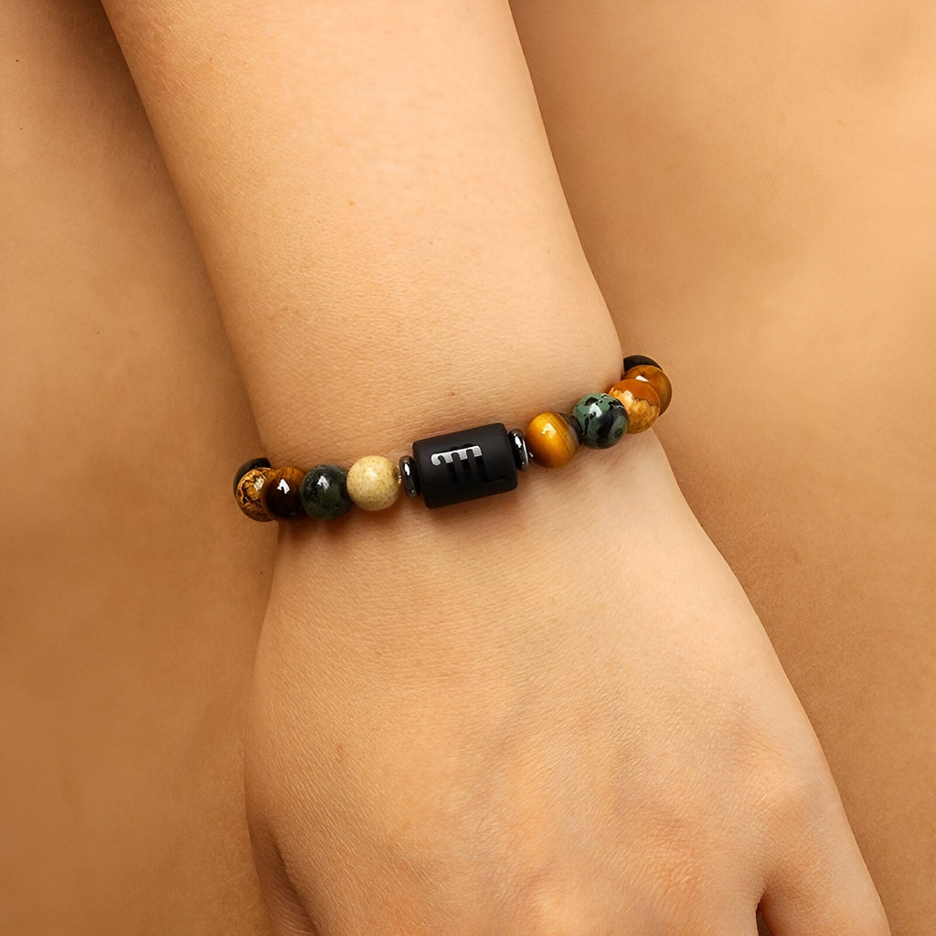 Bracelet mixte en pierres naturelles multicolores avec perle noire gravée sur poignet.