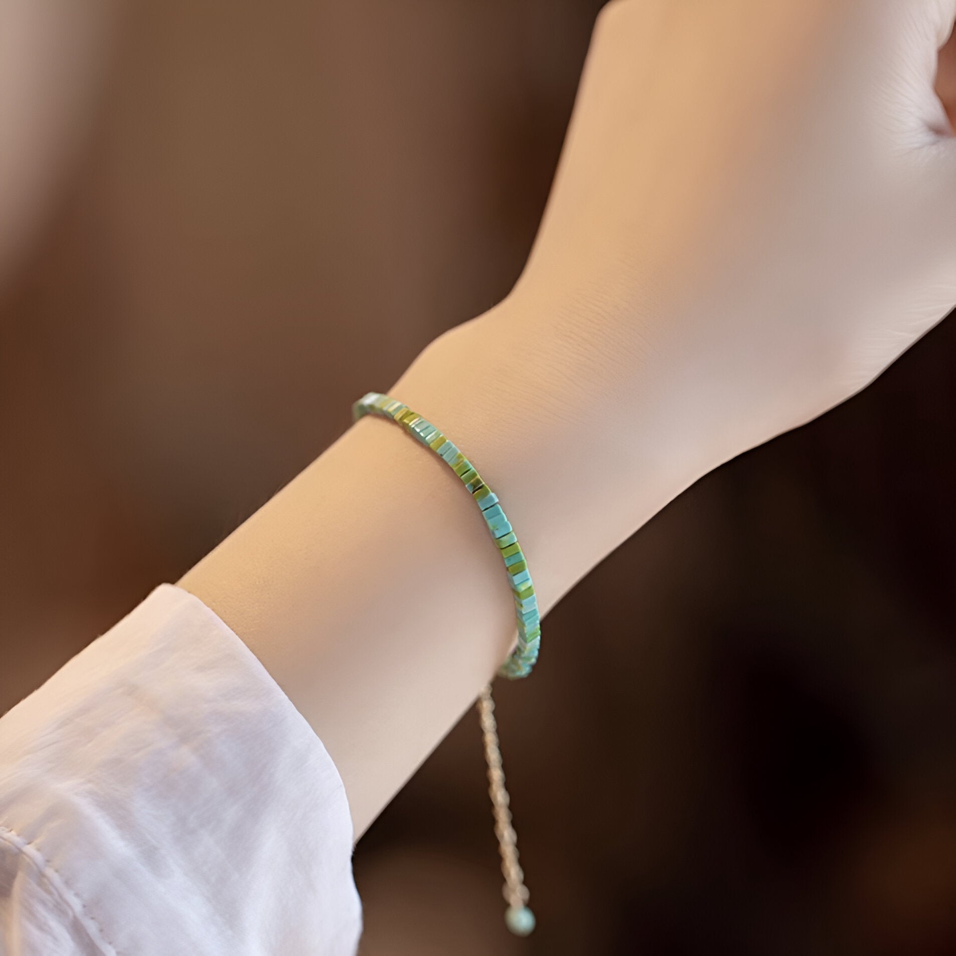 Bracelet fin en pierres turquoise et vertes, style discret, fermeture réglable avec perle blanche.