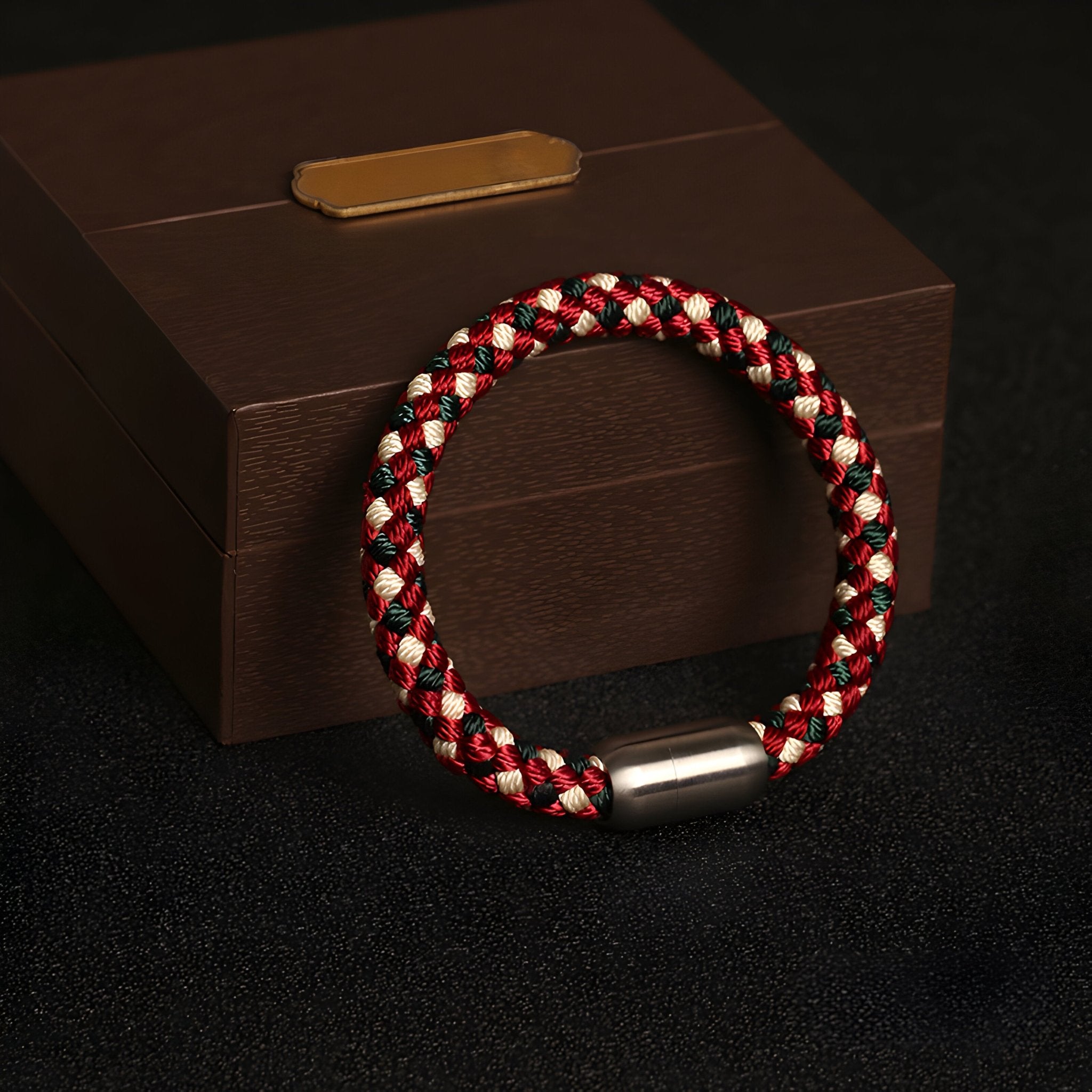 Bracelet tressé en polyester rouge, blanc et noir avec fermoir métallique argenté mat.