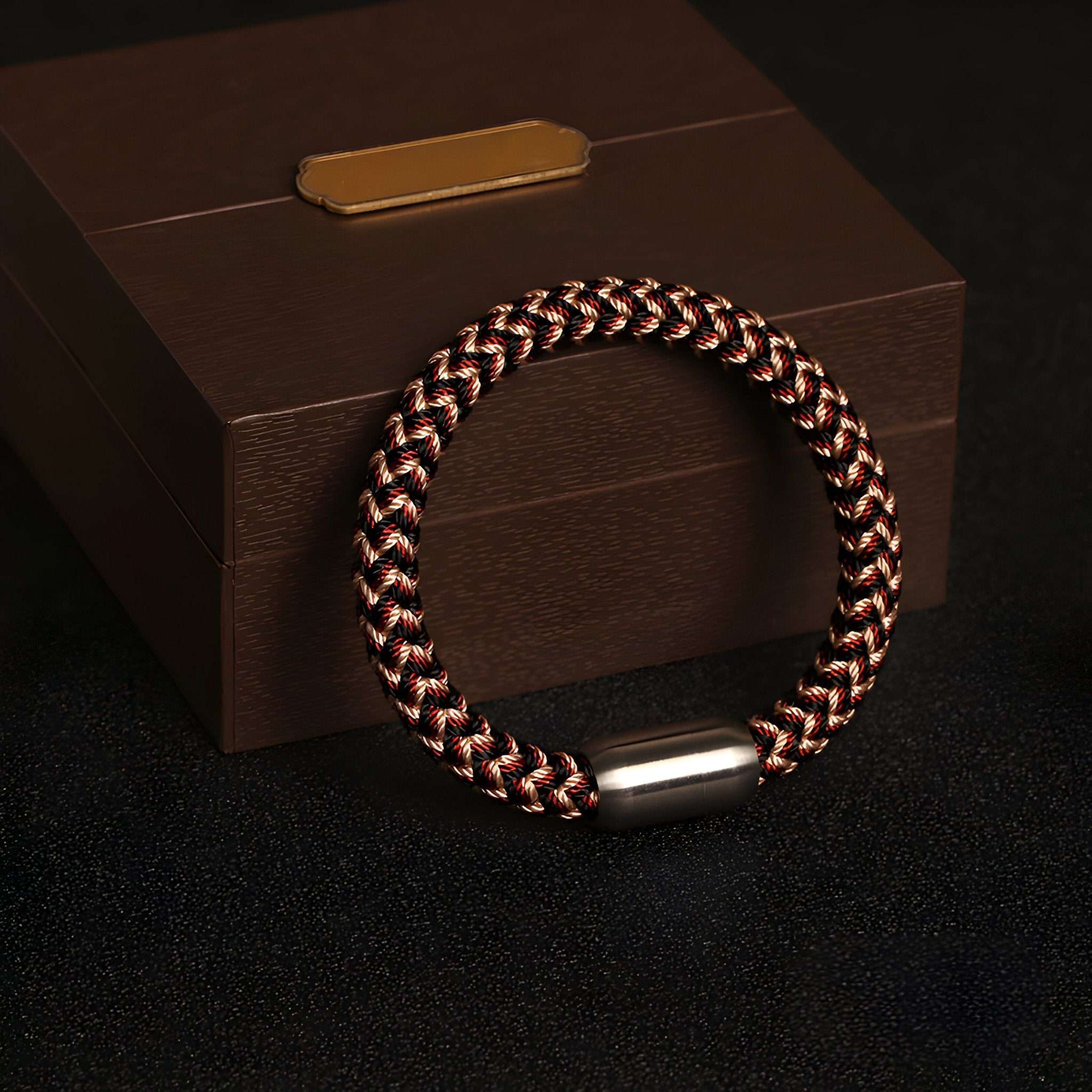 Bracelet mixte Marley tressé noir et marron avec fermoir argenté posé sur coffret marron élégant.