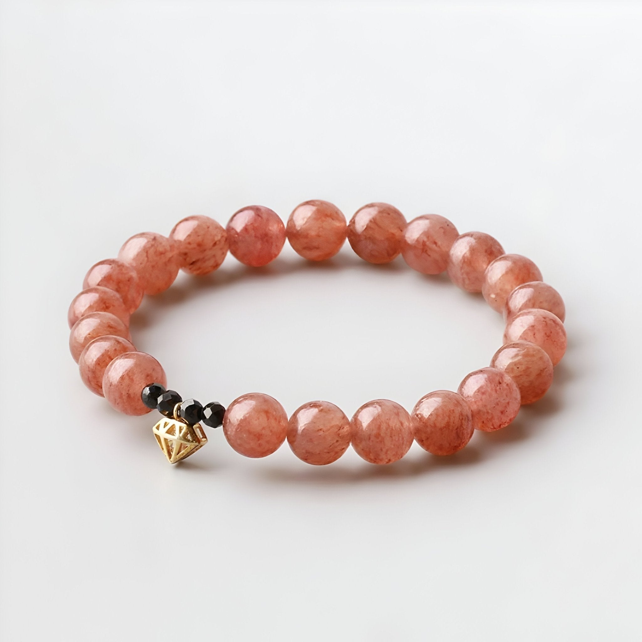 Bracelet femme perles rondes quartz rose avec pendentif cœur doré et perle noire.