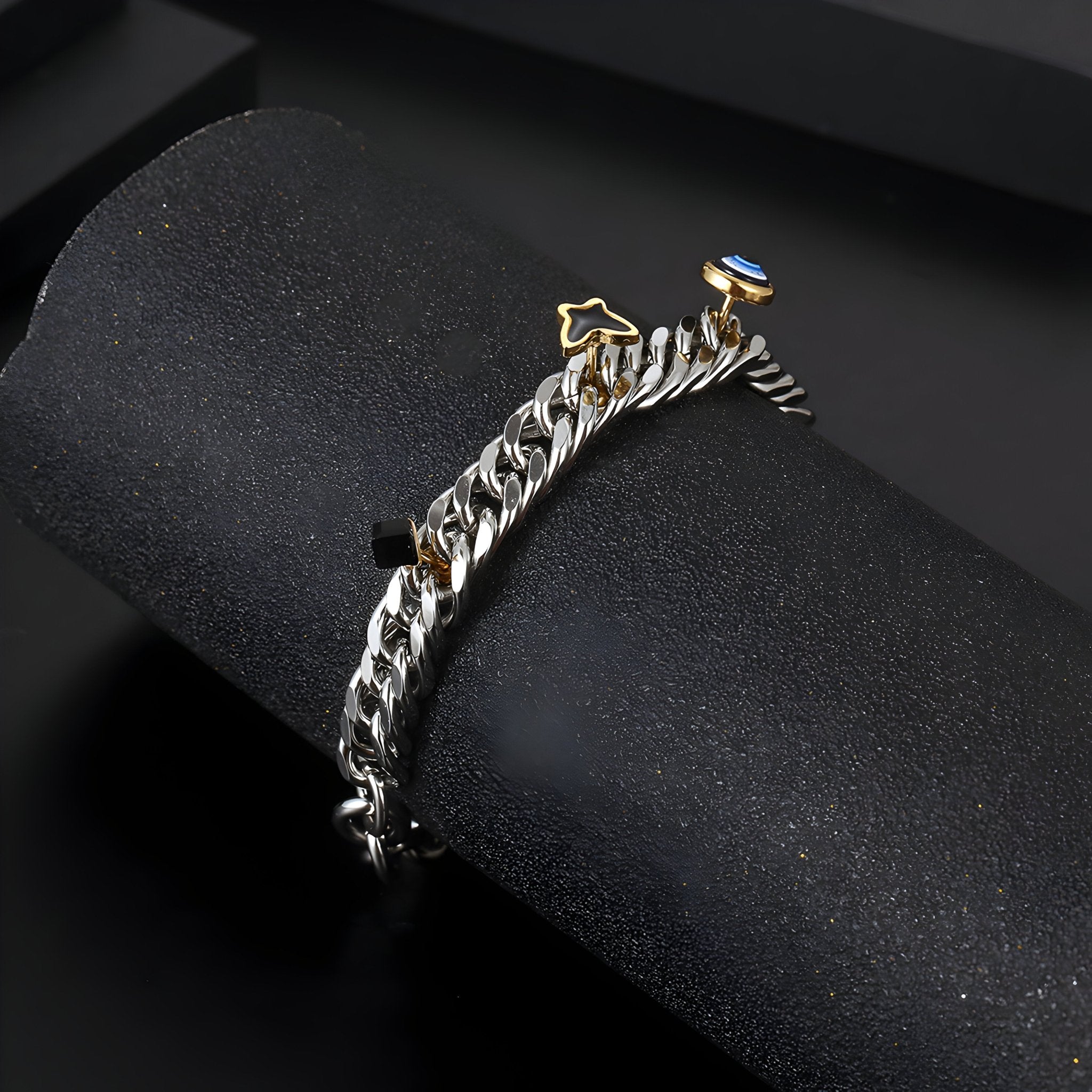 Bracelet en titane argenté avec charms œil et papillon dorés, style chaîne épaisse.