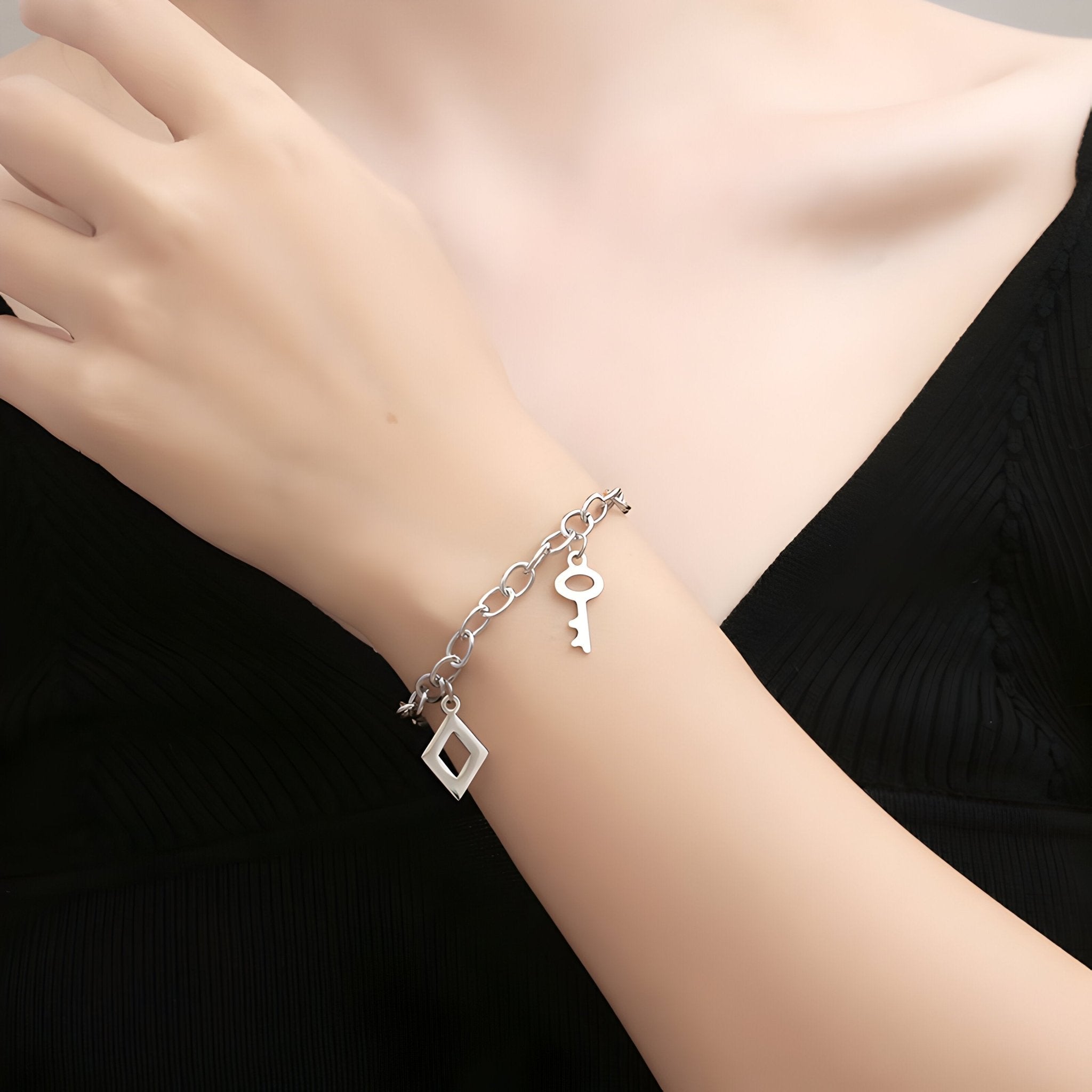 Bracelet en titane argenté double maille avec charms clé et losange, style élégant pour femme.