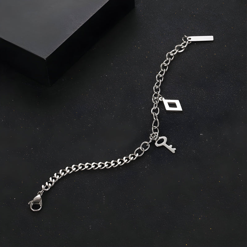 Bracelet en titane argenté à double maille avec charms clés et pendentif rectangulaire, fermoir mousqueton.