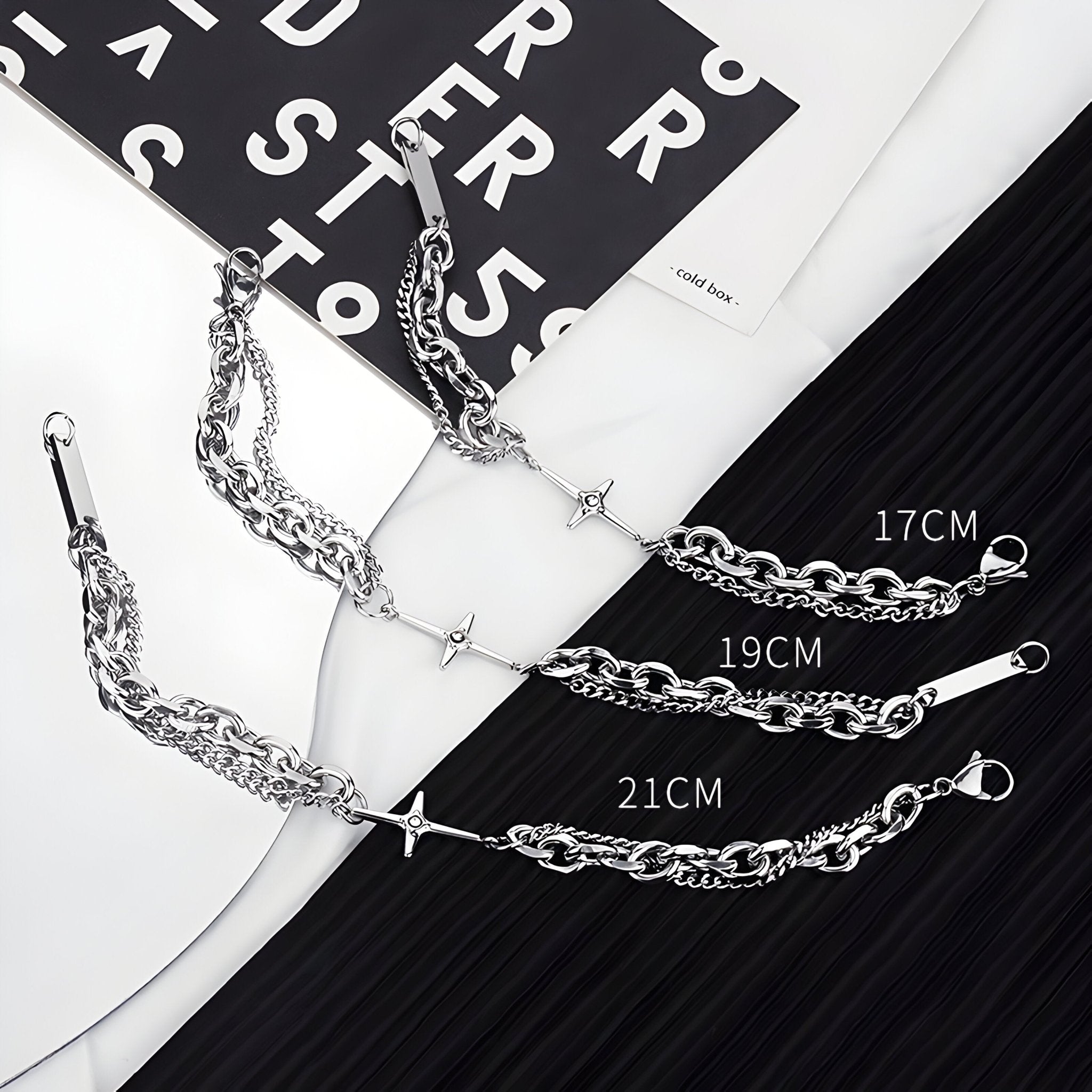 Bracelet homme en titane argenté à double maille avec croix centrale scintillante, tailles 17, 19 et 21 cm visibles.