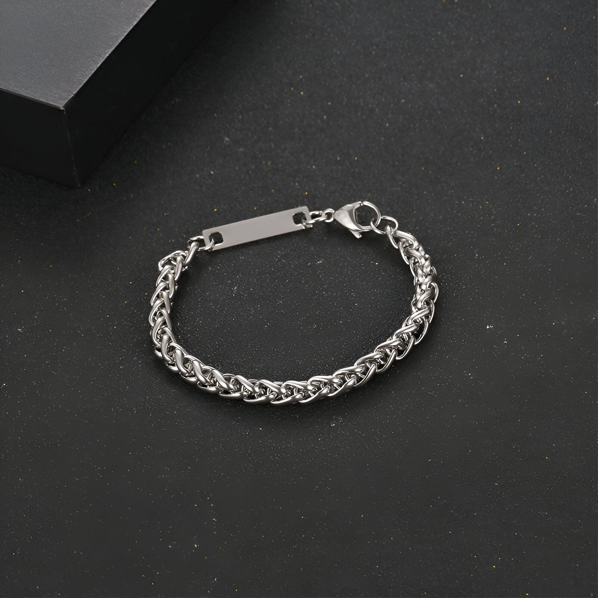 Bracelet gourmette mixte en titane couleur argent avec maille spiga et plaque gravée rectangulaire.