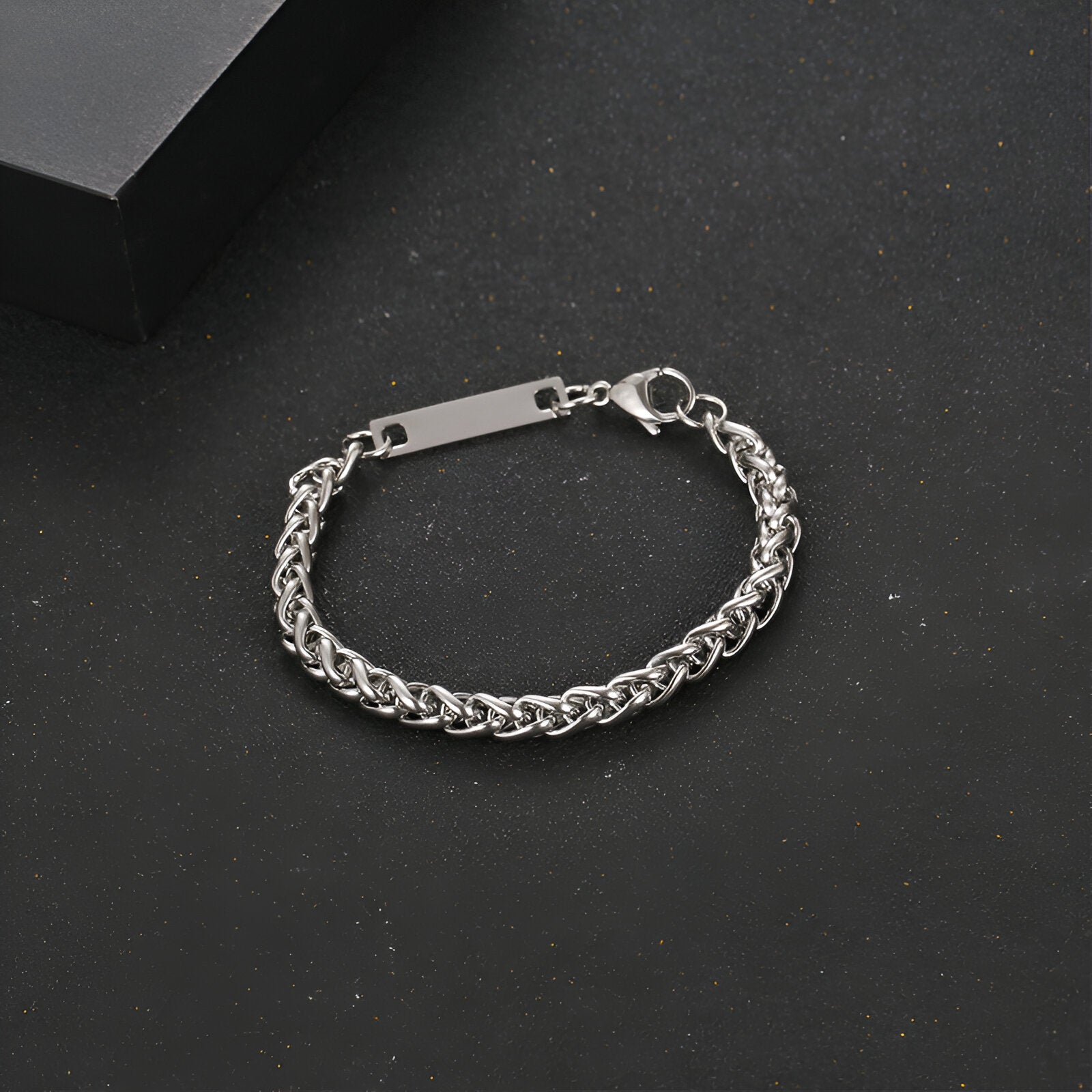 Bracelet gourmette mixte en titane couleur argent avec maille spiga et plaque gravée rectangulaire.