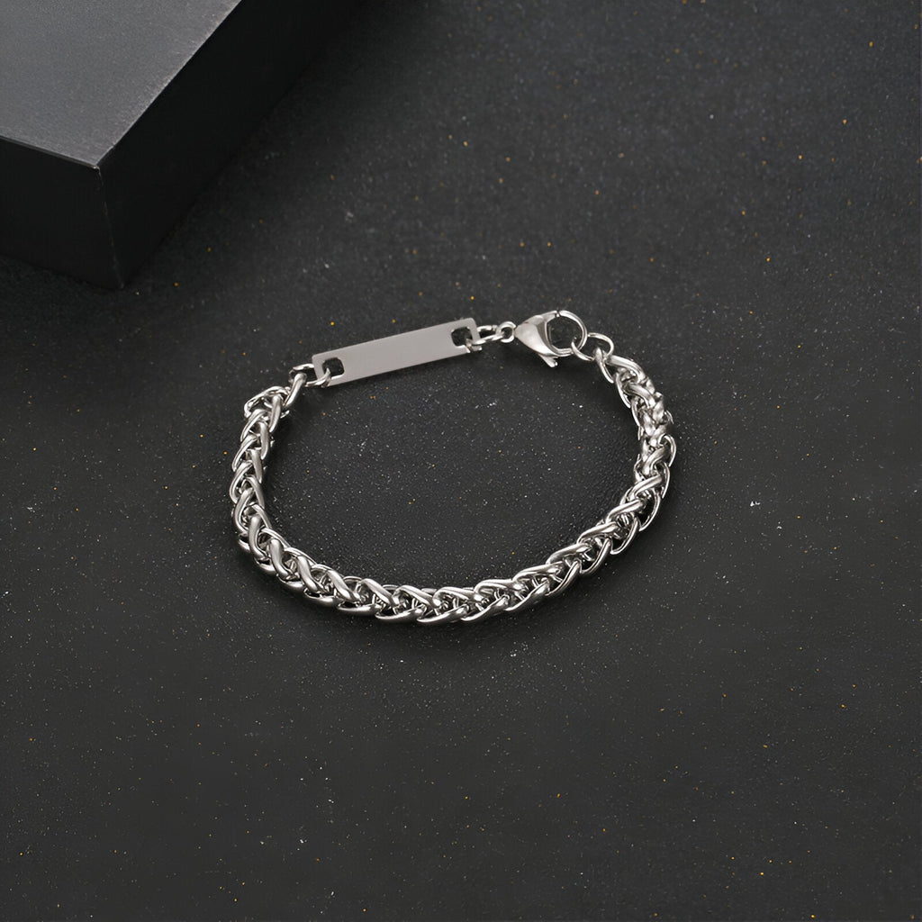 Bracelet gourmette mixte en titane couleur argent avec maille spiga et plaque gravée rectangulaire.