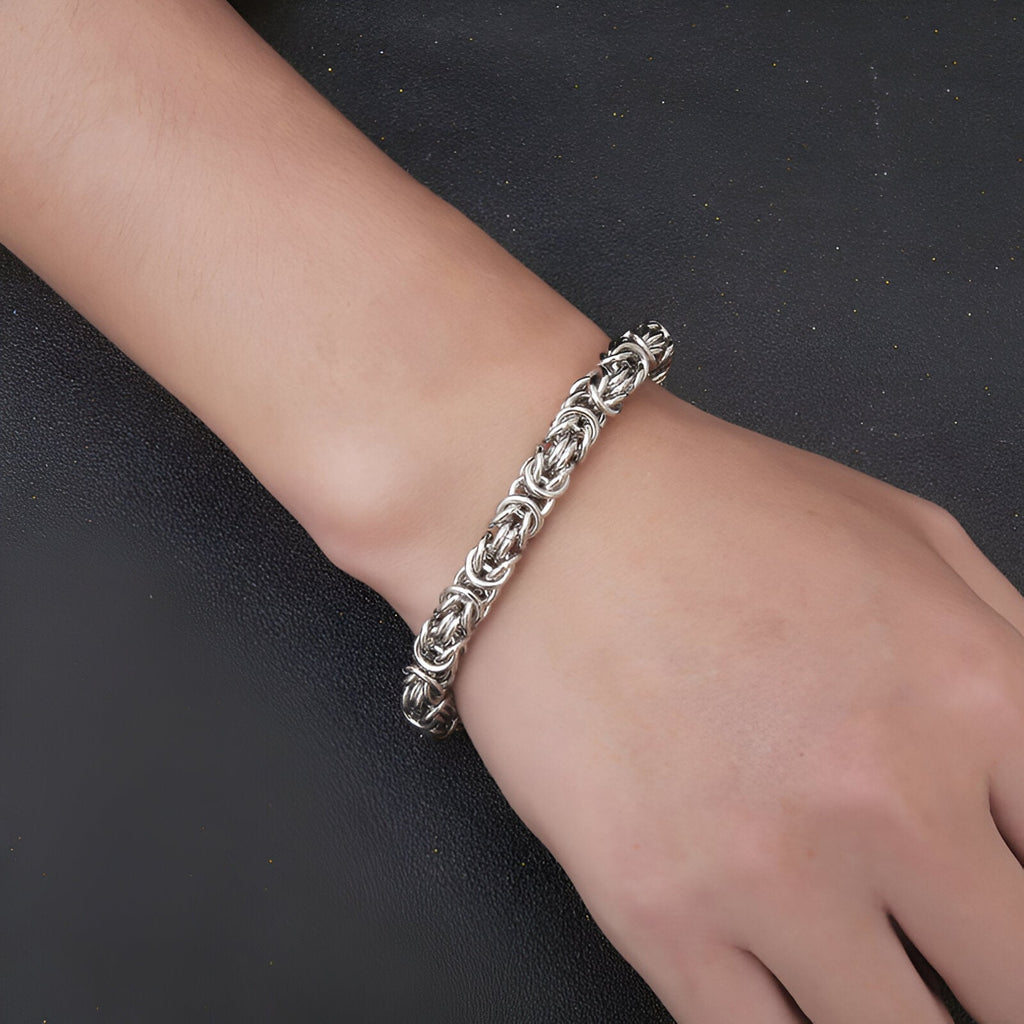 Bracelet en titane maille byzantine argentée, finition brillante, porté au poignet homme.