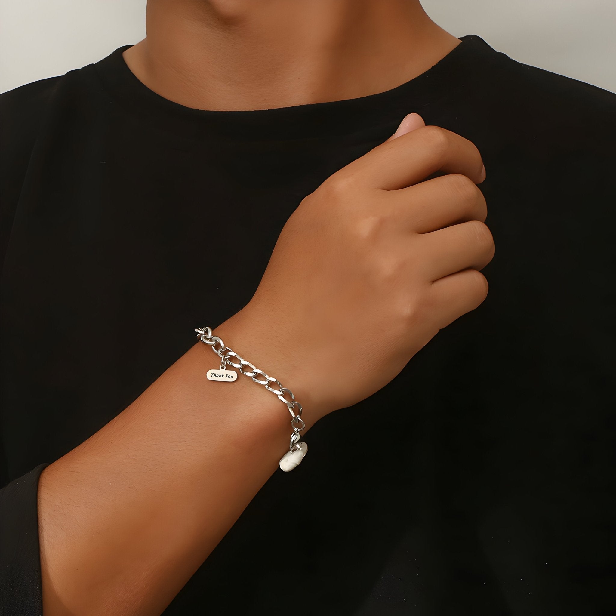 Bracelet homme en titane argenté à maille forçat avec pendentif cœur sur poignet.