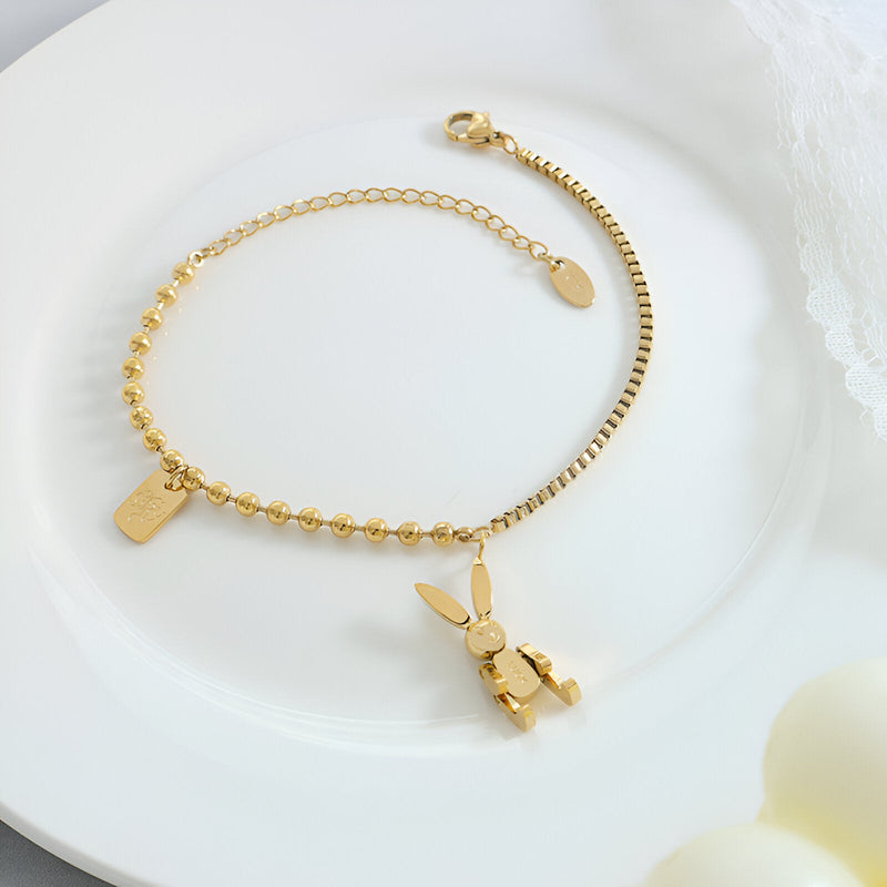 Bracelet en titane plaqué or 18 carats avec chaîne fine et charm lapin doré accroché.