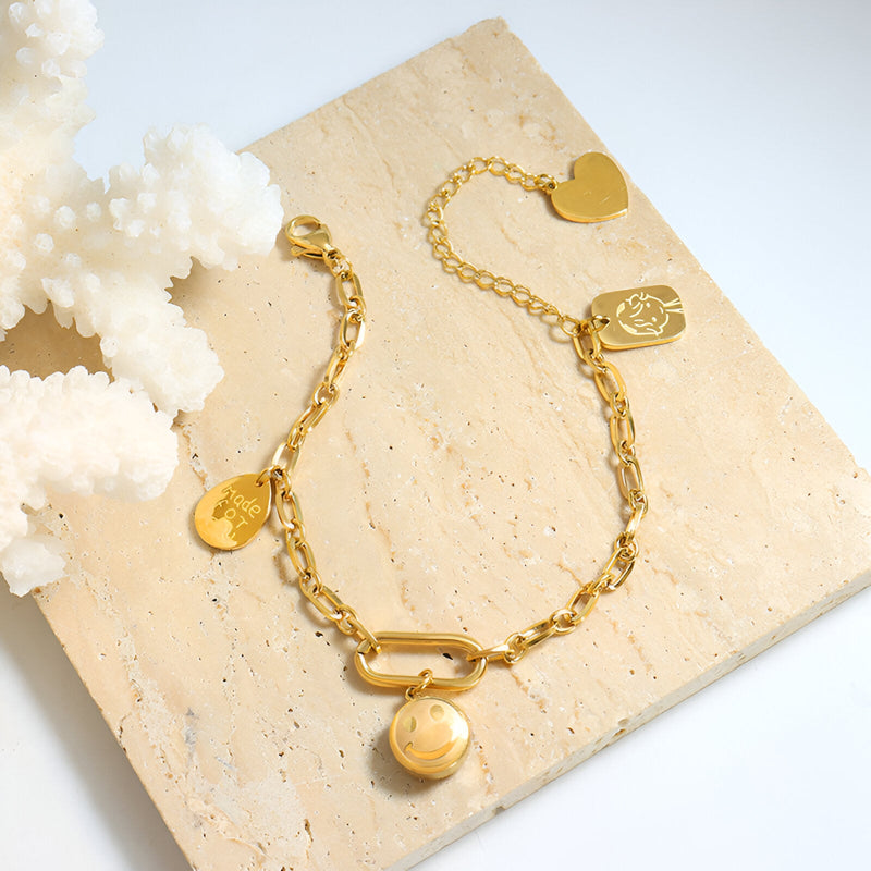 Bracelet en titane plaqué or 18 carats avec chaîne fine et médaillons ronds variés, fini brillant.