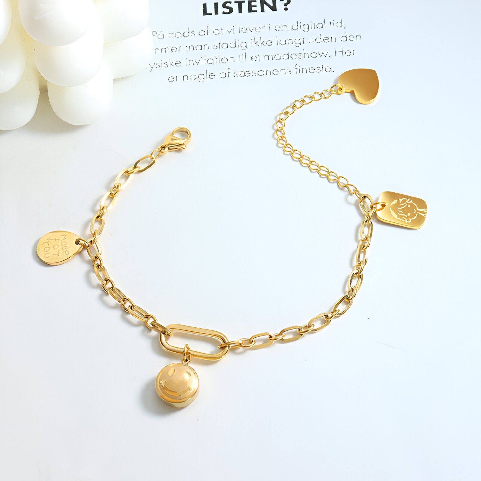 Bracelet or 18 carats en titane avec maillons ovales et médaillons variés, fermoir original en forme de boucle.