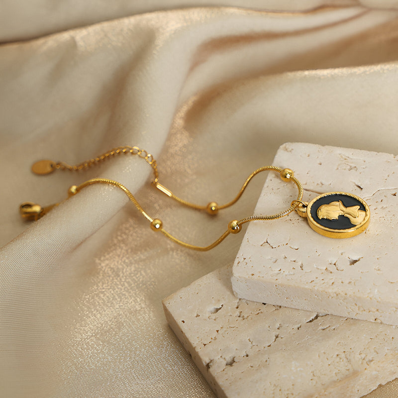 Bracelet en titane plaqué or 18 carats avec pendentif ovale noir et silhouette de Blanche Neige dorée.