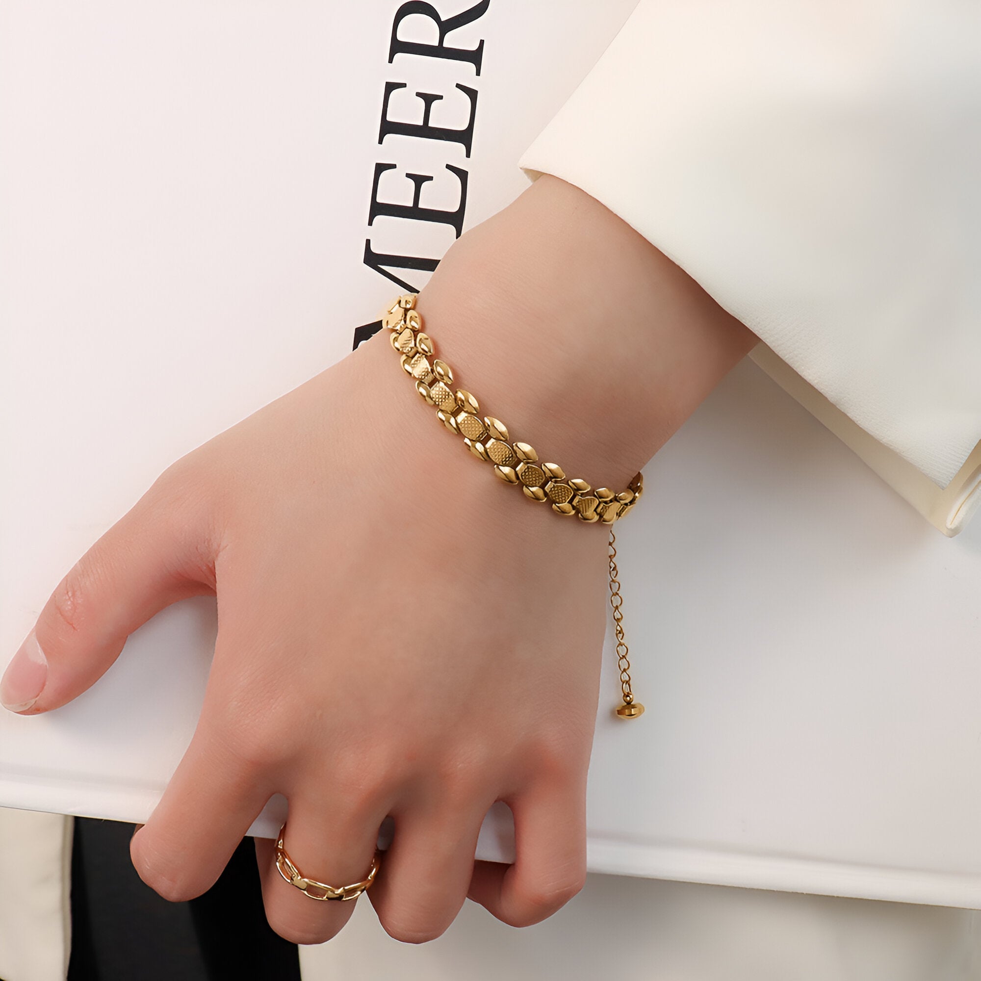 Bracelet en titane plaqué or 18 carats à maille épaisse avec chaîne de réglage, porté au poignet féminin.