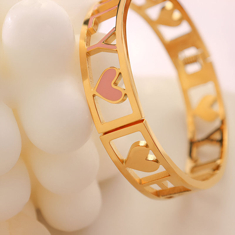 Bracelet fin en titane plaqué or 18 carats avec cœur rose et découpe géométrique élégante.