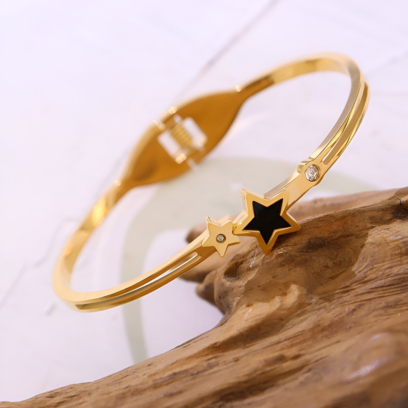 Bracelet jonc en titane plaqué or 18 carats avec étoile noire et petite étoile dorée sertie d’un cristal.