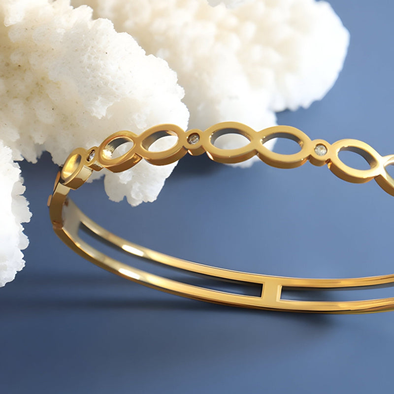 Bracelet en titane plaqué or 18 carats avec motif infini et pierres de zircon scintillantes.