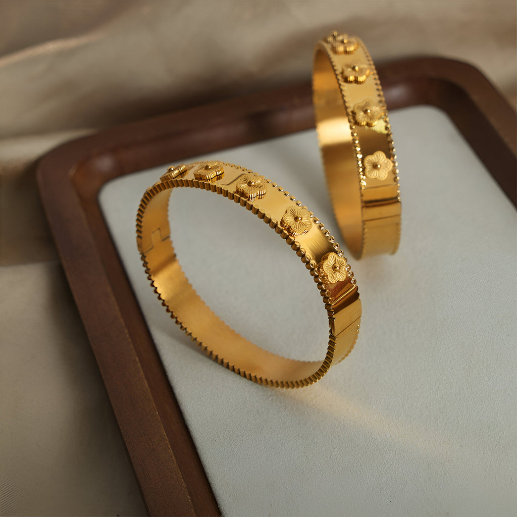 Bracelet jonc plaqué or en titane avec motifs fleurs en relief et bord dentelé.