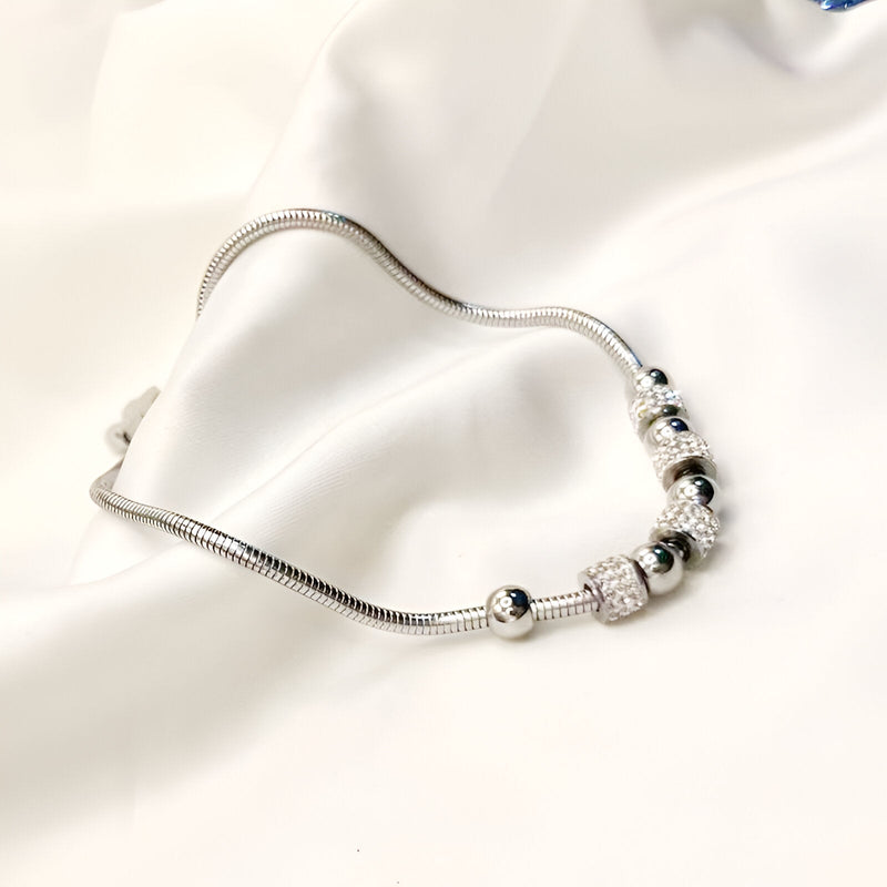 Bracelet en titane argenté avec perles et pierres de cristal brillantes, design élégant et raffiné.