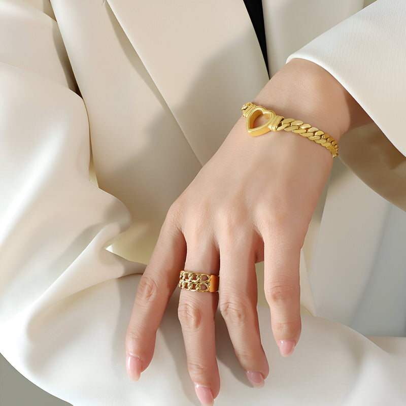 Bracelet en maille plaqué or avec motif cœur ouvert porté au poignet, style élégant et moderne.