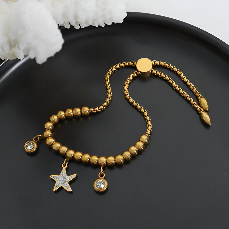 Bracelet en titane plaqué or avec perles rondes, médaillon étoile et pendentifs strass éclatants.