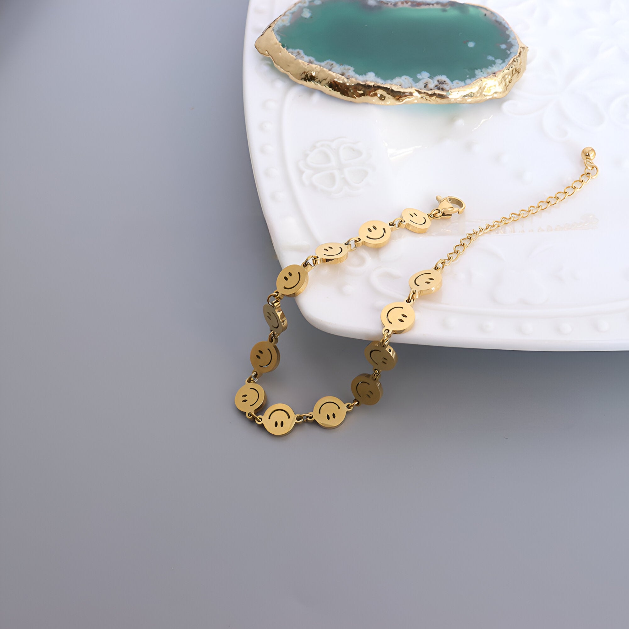 Bracelet en titane plaqué or avec motifs smileys ronds et chaîne de réglage élégante.