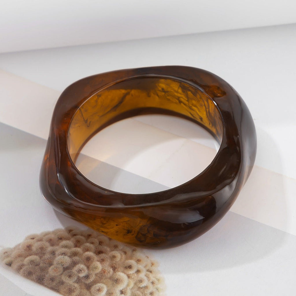 Bracelet femme épais en acrylique marron translucide avec forme ondulée élégante.