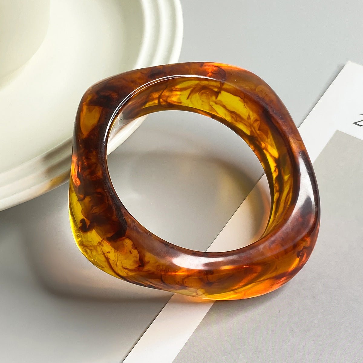 Bracelet épais en acrylique marron translucide avec effet marbré et forme géométrique irrégulière.