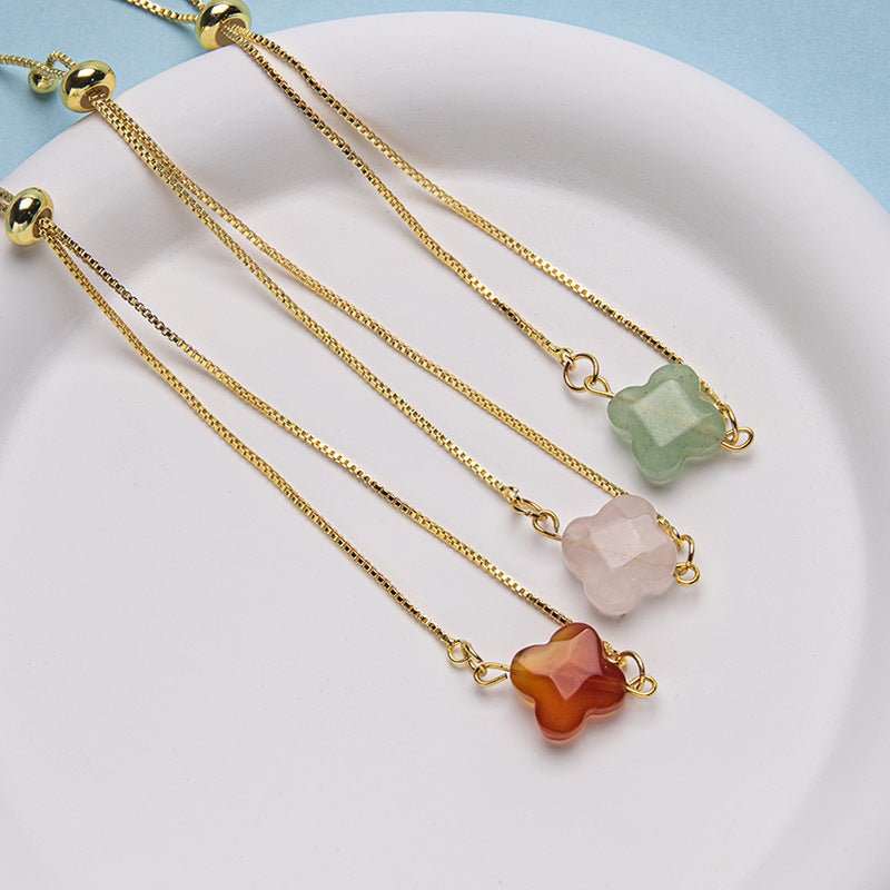 Bracelet à cordon doré avec pierre naturelle taillée en trèfle vert pâle, rose clair et rouge orangé, fermoir coulissant.