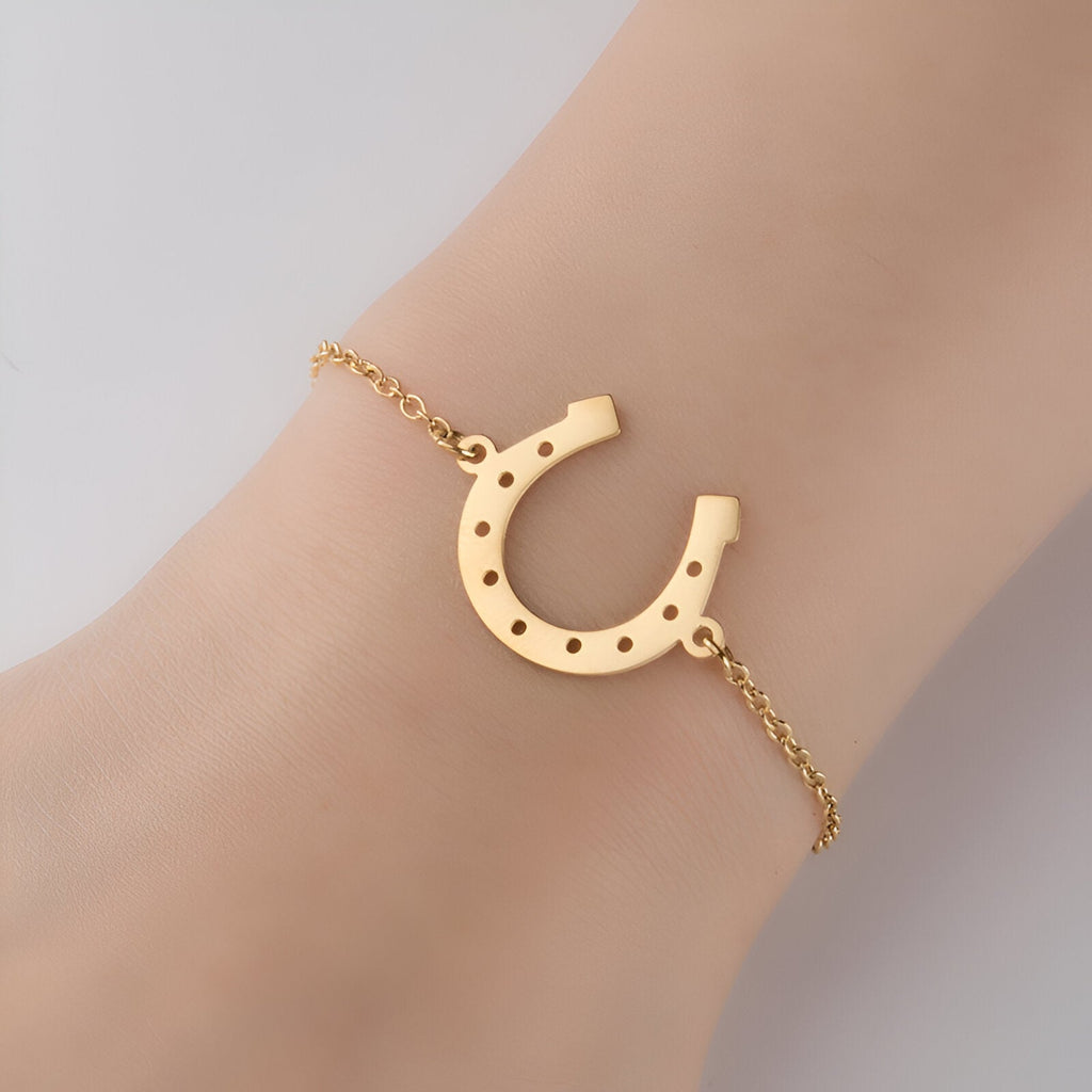 Bracelet chaîne fine en acier inoxydable doré avec pendentif fer à cheval ajouré.