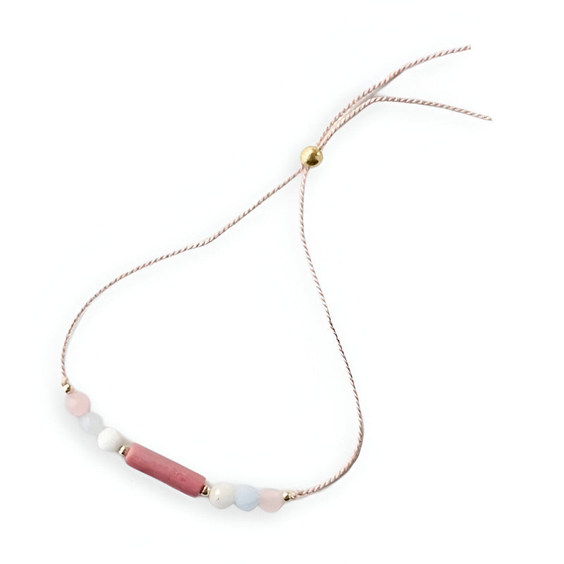 Bracelet fin rose en pierres naturelles avec perles rondes et tube allongé central doré.