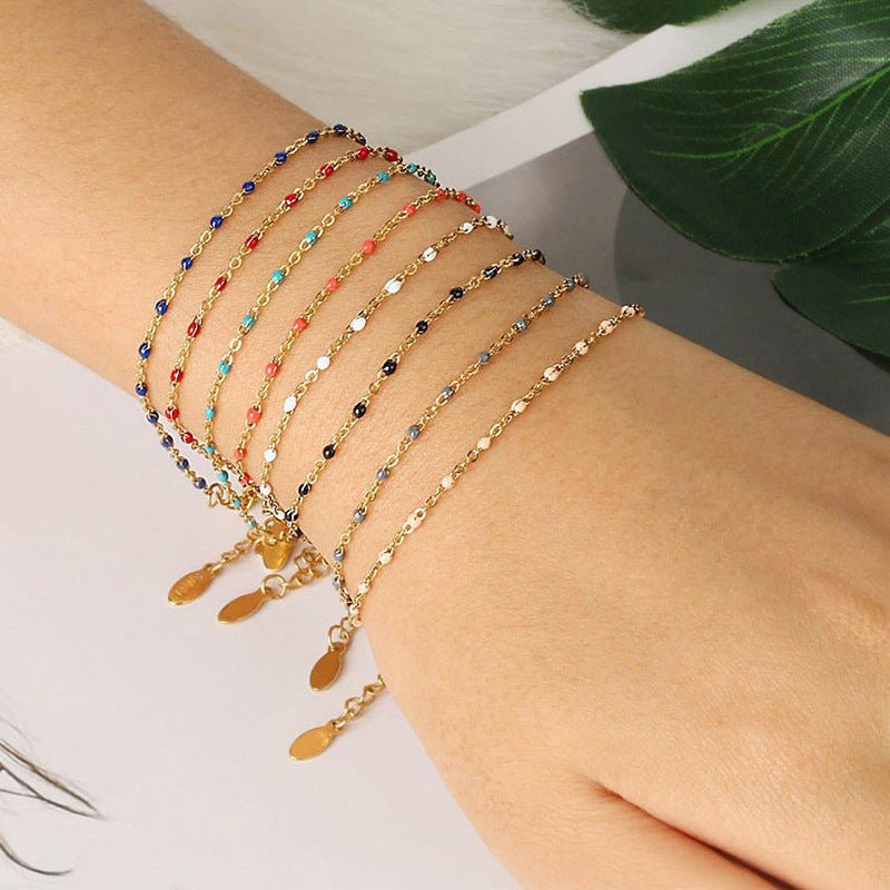 Bracelet fin doré en acier inoxydable avec maille forçat, perles colorées et fermoir mousqueton réglable.