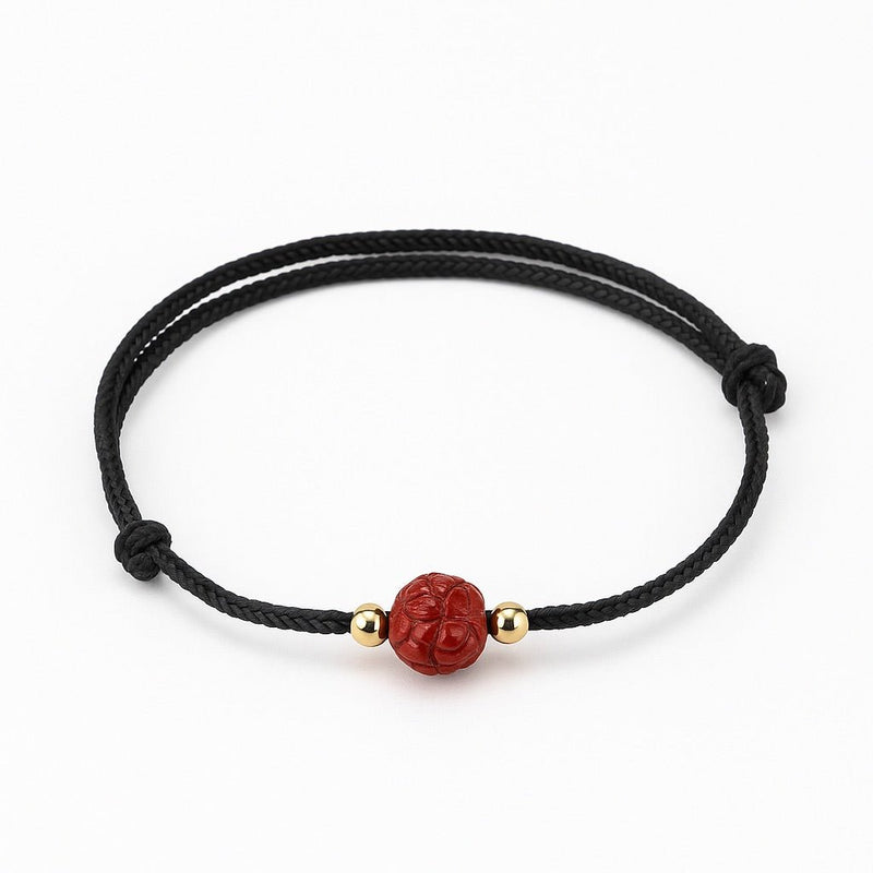 Bracelet noir en coton avec perle ronde rouge cinabre gravée fleur de lotus et petites perles dorées.