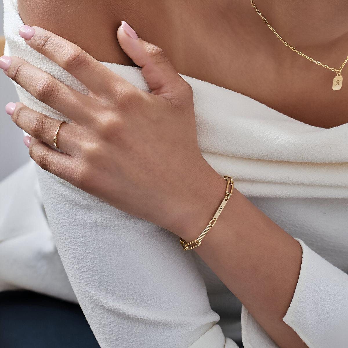 Bracelet gourmette or en acier inoxydable avec deux plaques personnalisées porté au poignet féminin.