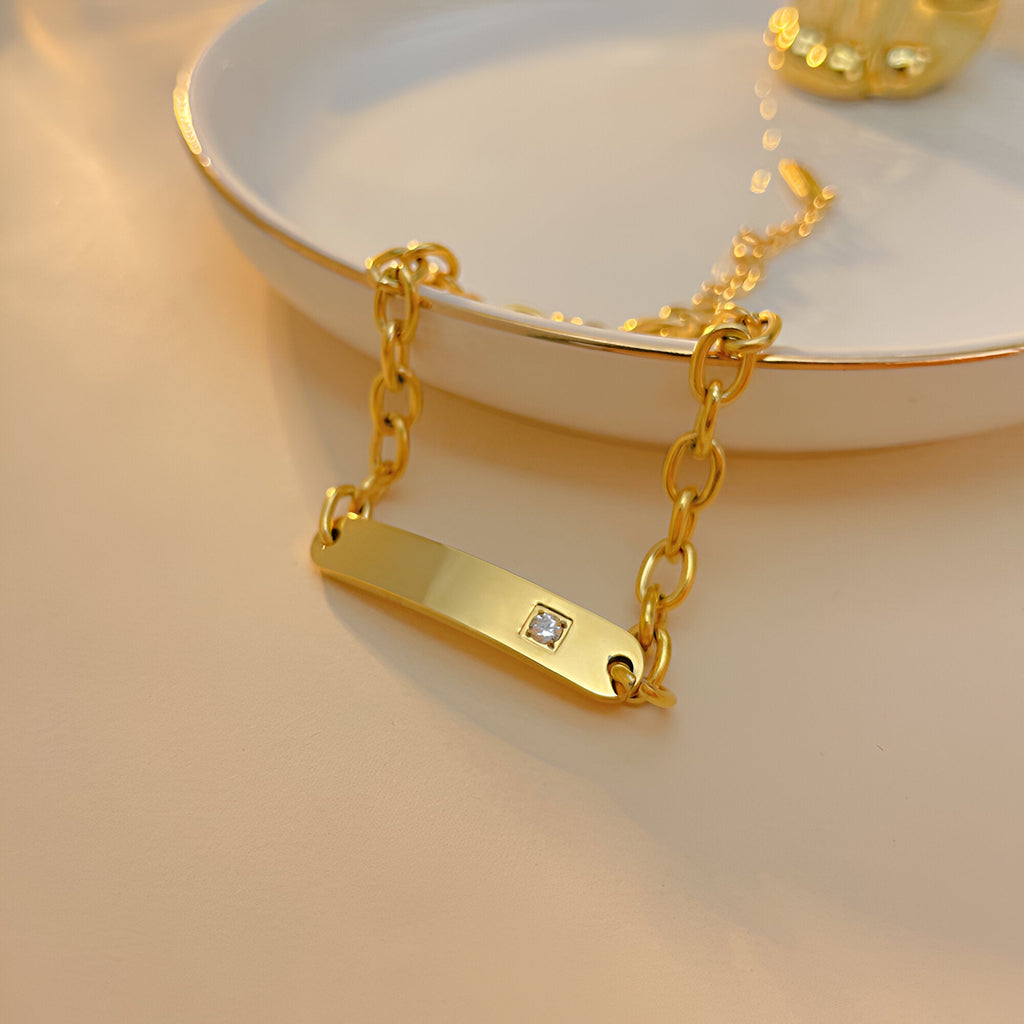 Bracelet gourmette en acier inoxydable doré avec pierre de zirconium carrée scintillante.