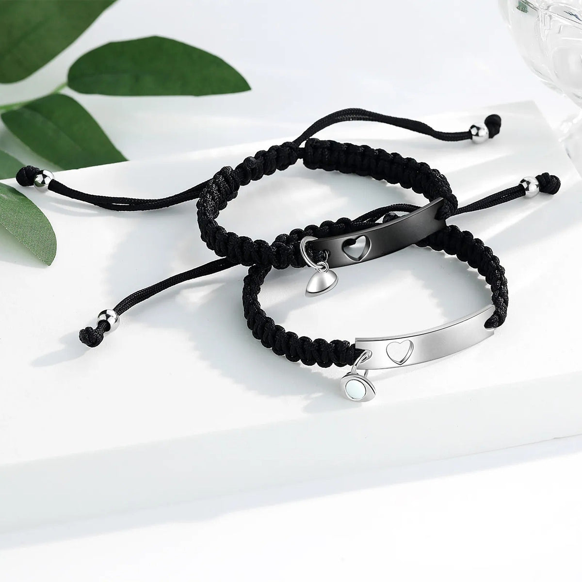 Bracelets gourmette en acier inoxydable noir et argent avec cordon tressé et pendentifs cœurs.