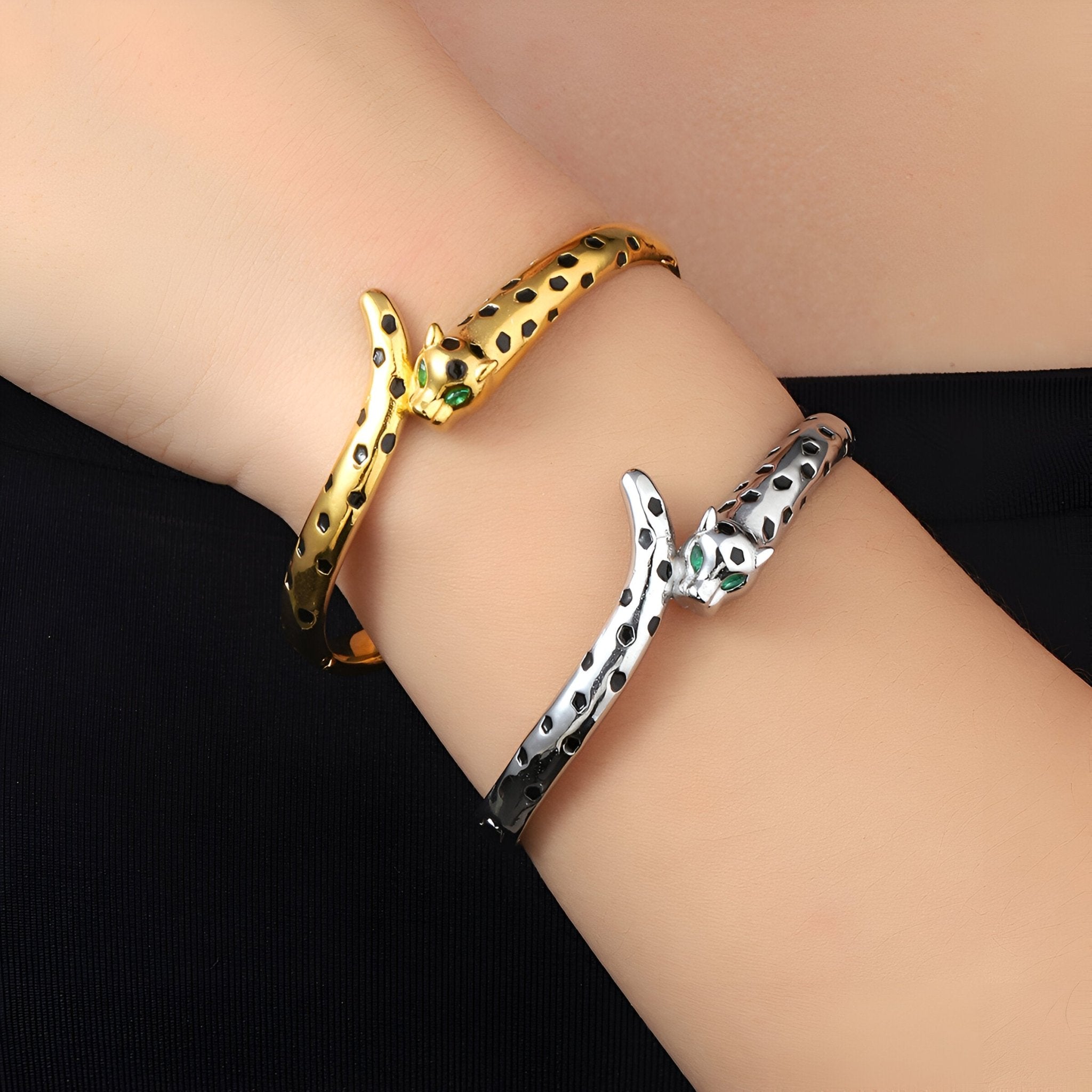 Bracelet jonc léopard doré à taches noires et bracelet jonc léopard argenté avec yeux verts sur poignet.