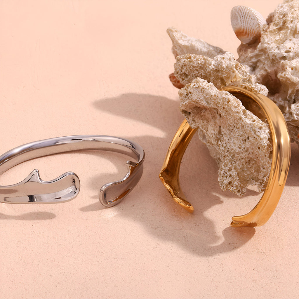 Bracelet jonc ouvert en acier inoxydable finition argentée avec design ondulé moderne .